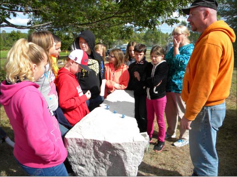 Sywalski explains his granite carving process to an attentive audience at a symposium. 