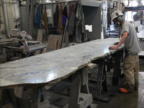 Brandon Osman is one of four shop men, shown here sizing up a slab fresh off the company’s eight-head polisher. Different levels of abrasive honing result in lighter or darker finishes. 