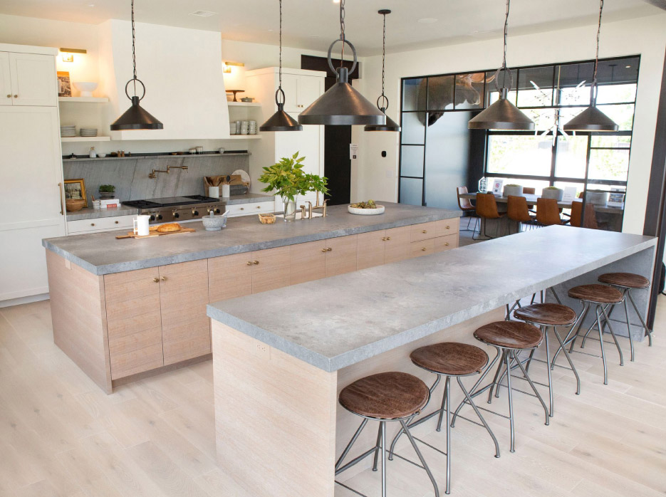 Two Quartz islands are designed as a modern, industrial contrast to the decorative quartzite stove counters and backsplash chosen in this kitchen and dining area