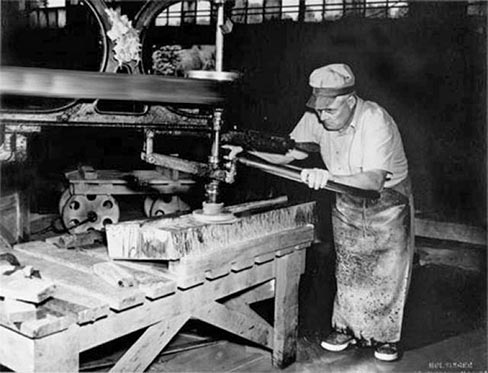 A stone worker grinds a custom piece with an early version of a single-arm polisher, and above, another adds counterweights to balance the polishing arm on a rubbing bed–one of the interesting machines still preserved at the Schuyler operation, now thoroughly modernized with surface polishers and other essential processing equipment to bring industry-sized slabs to a growing market.