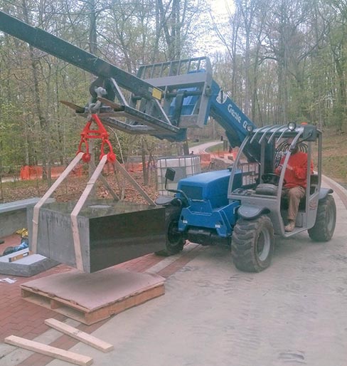 A high-lift fitted with a Braxton-Bragg boom gently lifts the pedestal on the day of its placement, just one week prior to the dedication. “After mounting the EGA, we then took everything to Virginia and installed it ourselves,” explained Stan. “We did the landscaping as well.” William Stone and Tile was also responsible for the brick pavers and retaining wall clad in stone.
