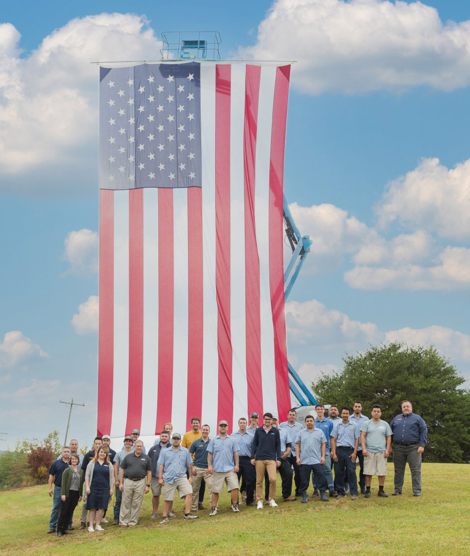 The Upstate Granite Solutions crew gathers in front of their specially sewn 50 x 80 foot American flag.