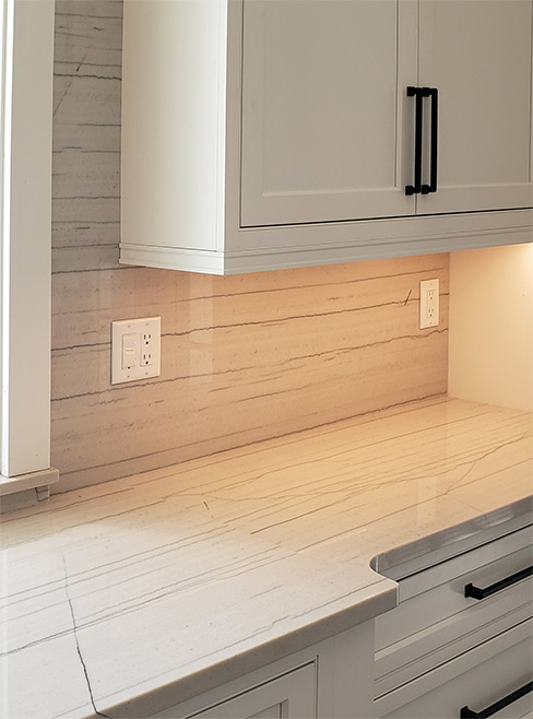 White Macaubas Quartzite kitchen includes a built-in farmhouse sink, a full-height backsplash around the windows, and pop-ups on the large island.