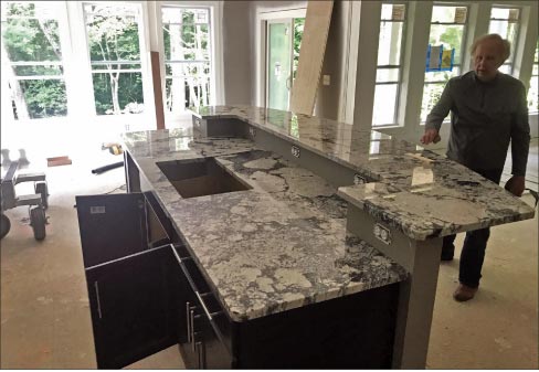 Fred Skeeles checks out a custom Abstract White granite island, just installed in a new build for 3 Pillar Homes.