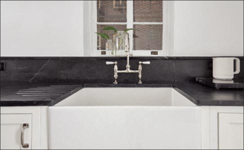 This white cast iron apron sink is paired with oiled soapstone countertops featuring a beautifully functional carved drainboard.