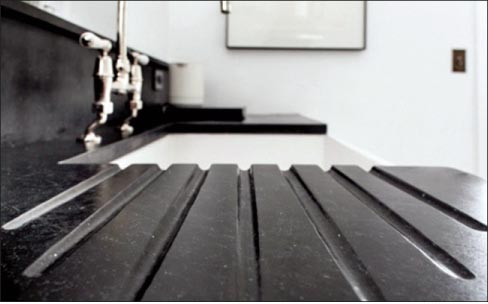 This white cast iron apron sink is paired with oiled soapstone countertops featuring a beautifully functional carved drainboard.