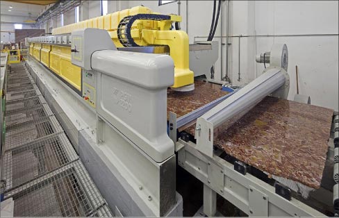 This polishing line at a slab processing plant is applying a uniform “factory finish” to slabs, prior to distribution.