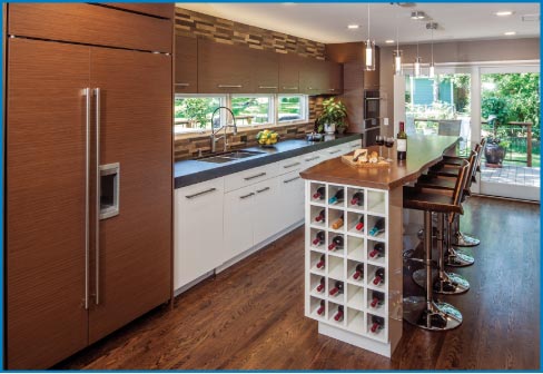 Honed granite countertops and a natural-edge wood bar create a sophisticated, modern look in this warm, wood-filled kitchen space.