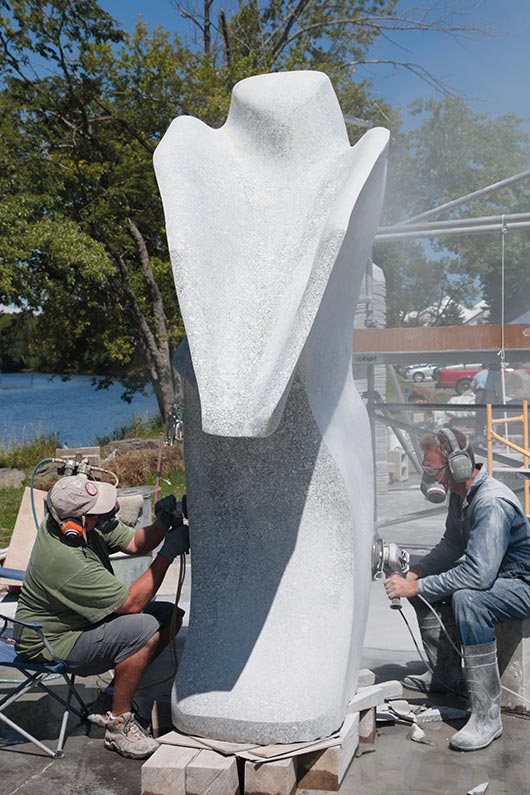 Andreas Von Huene (at right) grinds and shapes a curve, and assistant Richard Reichenbach wet polishes the in-progress sculpture